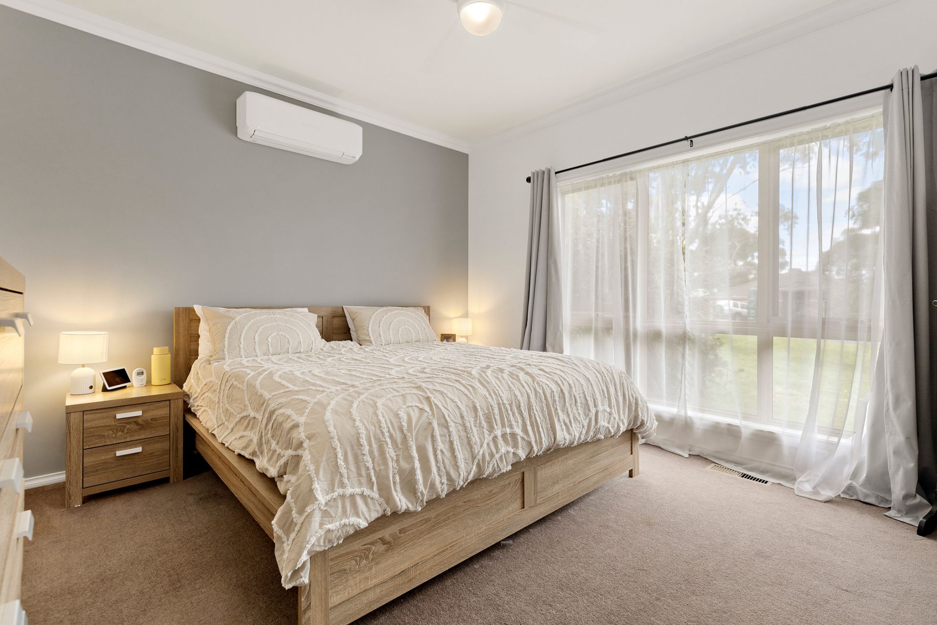 Premium bedroom with a modern wall-mounted split system air conditioner above the bed