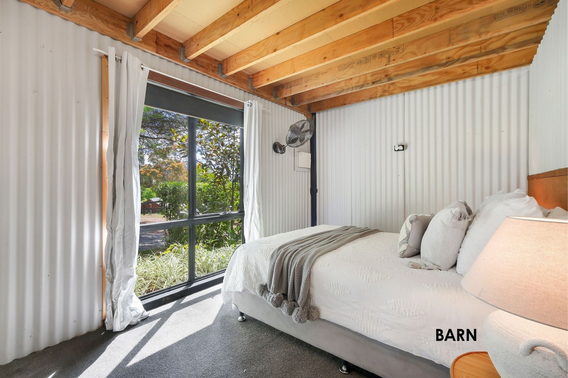 Melody Park barn — bedroom and lounge space, corrugated iron walls, warm fit-out
